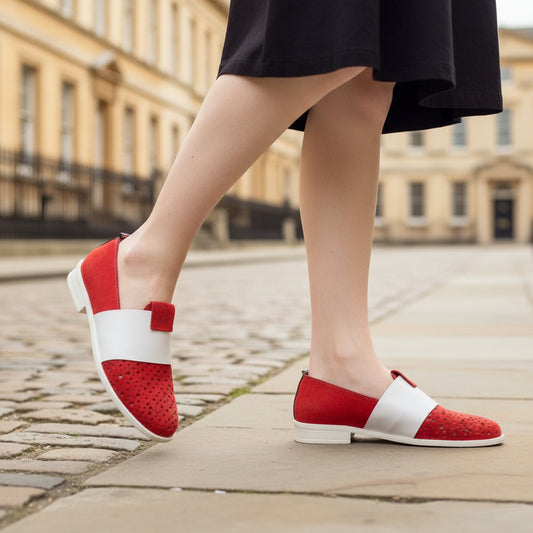 Red and white shoes worn by a person standing on a stone path with a stone wall background.
