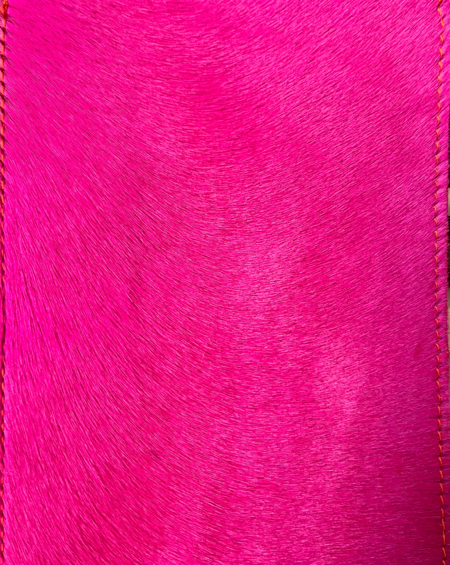 Close up of the colour and texture of the fuchsia cowhide black messenger bag