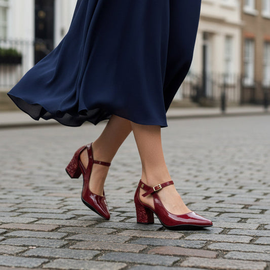 Person wearing a navy blue dress and red shoes on a street.