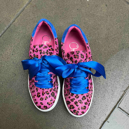 Pink leopard print sneakers with blue laces on a gray pavement.