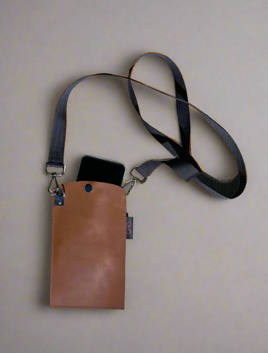 Brown pouch with black strap on a wooden surface