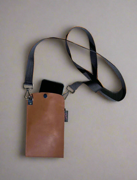 Brown pouch with black strap on a wooden surface