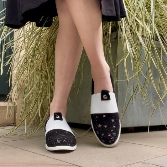 Person wearing black and white shoes with star patterns on a pavement background