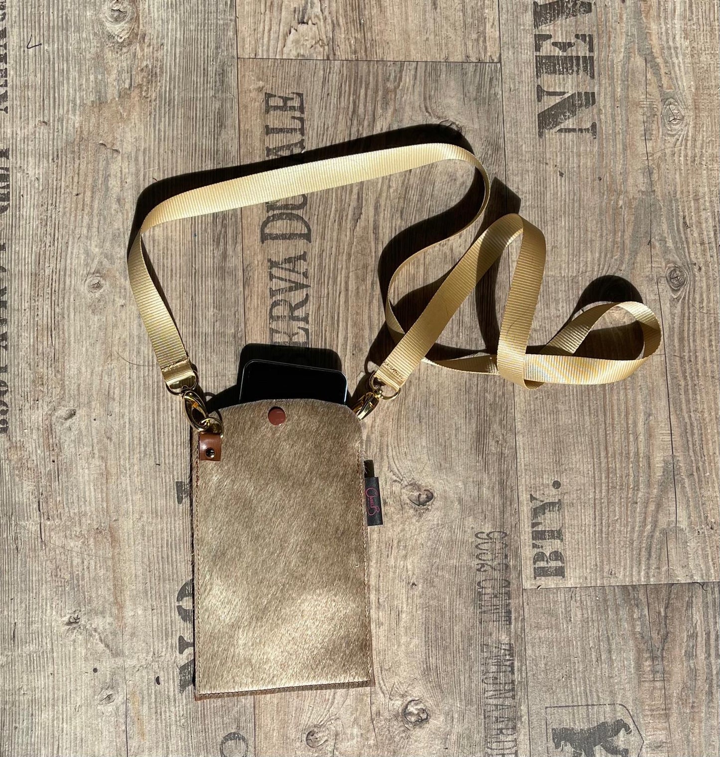 Small leather pouch with gold strap on a wooden surface