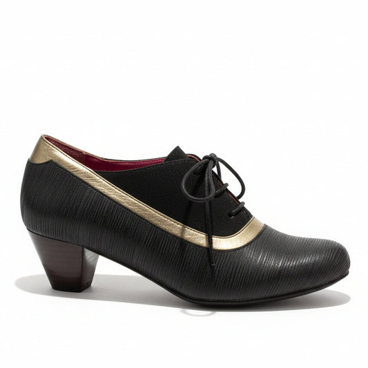 Brown shoe with gold trim on a stone floor